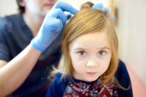 Doctor examines child hair and scalp for lice and nits. Pediculosis is common disease in kids groups